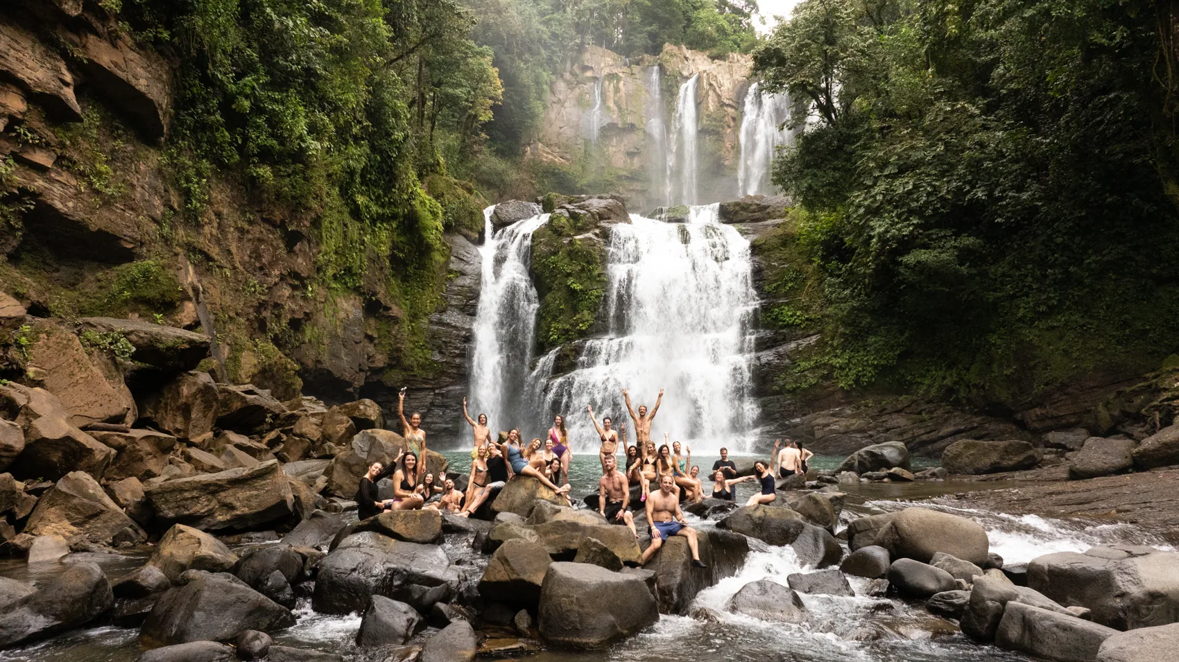 A retreat group on the rocks below a waterfall